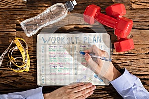 Person Making Note Of Workout Plan On Notebook