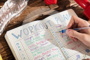 Person Making Note Of Workout Plan On Notebook