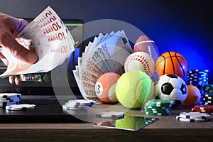 Person making online sports bets on desk with sport objects