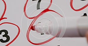 Person marking date circling red marker in calendar, closeup
