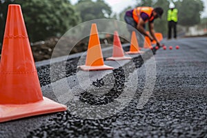 person marking freshly laid asphalt with boundary cones