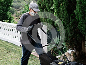 Person with mask is preparing the garden with an electric mower