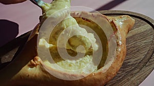 person mixing suluguni cheese and egg yolk in georgian adjarian khachapuri