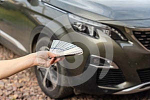 Person with money in the hands standing front car. Insurance, loan concept. Deal of buy or rent new car