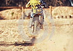 Person, motorcyclist and dust with dirt bike on track for race, extreme sports or outdoor competition. Rear view of