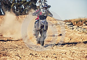 Person, motorcyclist and dust with motorbike on dirt track for race, extreme sports or outdoor competition. Professional