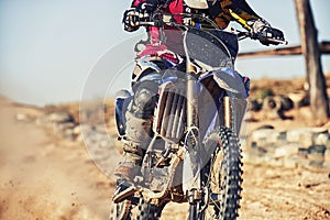 Person, motorcyclist and track with dirt bike for race, extreme sports or outdoor competition. Closeup or legs of expert