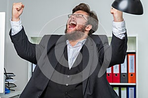 Person in an office bursts out in jubilation and pulls his arms up in the air