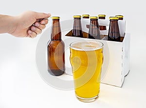 A person opening a Pilsner Style Lager brown bottle sic pack with a full pint of beer