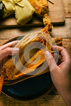 Person opening a tamale with his hands.