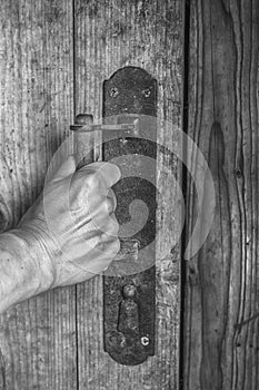 A person opens door of a wooden hand with an old handle