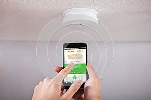 Person Operating Smoke Detector With Mobile Phone