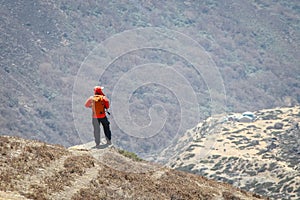 Person in orange windbreaker stands on mountainside in Himalayas