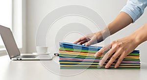 Person organizing colorful folders on a white desk in an office setting