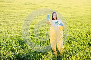 Person in overalls holds paper with a call to save the planet while standing on green field on sunset and the other hand shows a