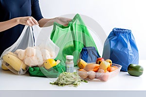 person, packaging products they have purchased into reusable bag or basket