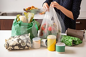 person, packaging products they have purchased into reusable bag or basket