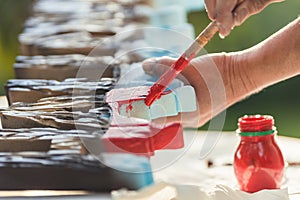 Person painting polystyrene letters in red outside photo