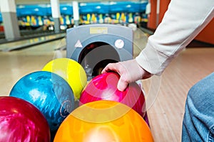 Person picking bowling ball from rack