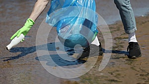 Person picking plastic bottle from water sea ocean and throwing it in bag Spbi. closeup of volunteer