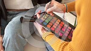 Person picking up powder from the palette of make-up kit