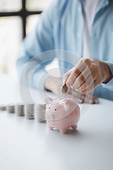 Person with pile of coins and piggy bank, money saving concept for future use.