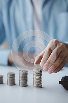 Person with pile of coins and piggy bank, money saving concept for future use.