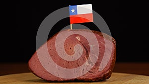 Person placing decorative Chilean flag toothpicks into piece of red meat.