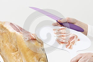 Person with a plate in his hands, cutting ham