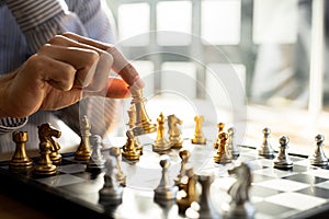 Person playing chess board game, business man concept image holding chess pieces like business competition and risk management,