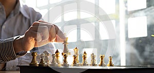 Person playing chess board game, business man concept image holding chess pieces like business competition and risk management,