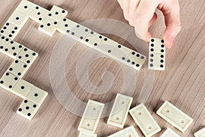 Person playing dominoes on a wooden table
