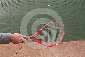 Person playing wall tennis hitting a tennis ball with tennis racket
