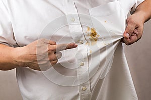 Person pointing to spilled curry stain on white shirt.