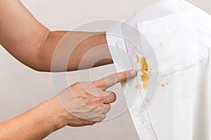 Person pointing to spilled curry stain on white shirt.