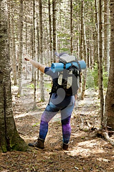 Person points in their direction in the woods while hiking