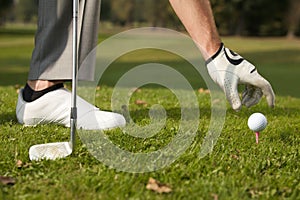 Person positioning golf ball on tee photo