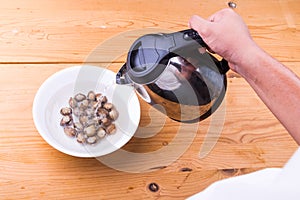 Person pouring boiling water over cockles in bowl