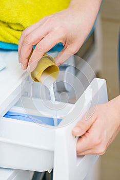 Person pouring fabric softener into washing machine