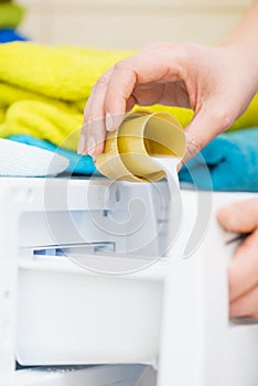 Person pouring fabric softener into washing machine