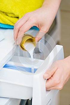 Person pouring fabric softener into washing machine