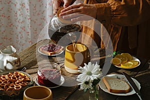 Person pouring tea from teapot during morning breakfast.