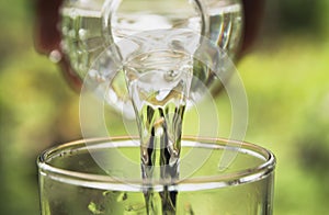 Person pouring water from bottle to glass on nature