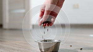 Person pours dry pet food into bowl.