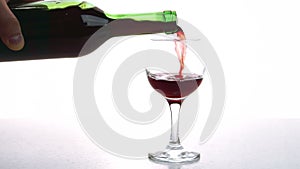 Person pours red wine into glass in room of appartment.