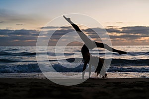 Person practicing yoga poses at sunset on a sandy beach.