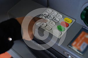 Person pressing pin code on ATM bank machine
