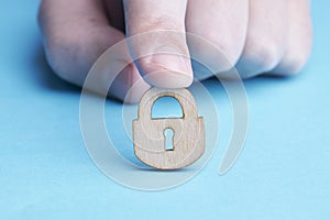 person privacy and security concept. caucasian person holds wooden padlock over blue background. copy space