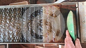 Person processing gold sand in a waterfall conveyor