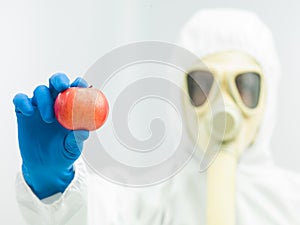 Person in protective suit holding ripe apple